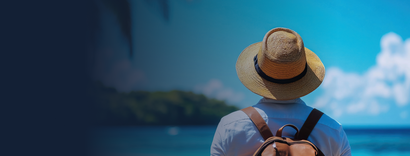 Pessoa de costas com chapéu de palha e mochila marrom contemplando paisagem tropical com mar azul e ilha ao fundo.