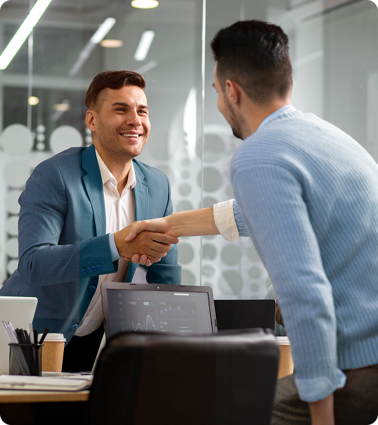 Dois homens se cumprimentando com aperto de mão em ambiente de escritório.